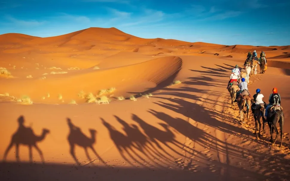 Sunset over red dunes on the best desert safari Dubai with a 4x4 and sandboard tracks