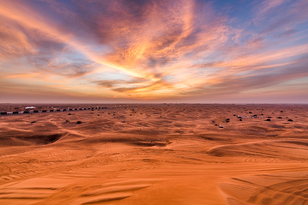 Sunrise glow over red dunes during a Desert Dubai tour