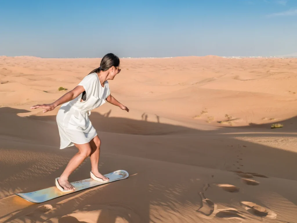 Traveler enjoying sandboarding Dubai on golden desert dunes