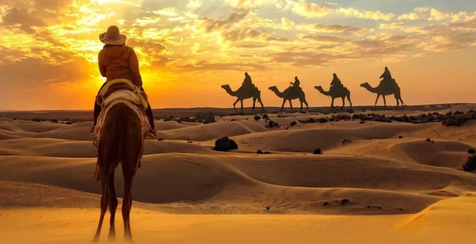 Tourist enjoying a camel ride Dubai experience across golden desert dunes at sunset