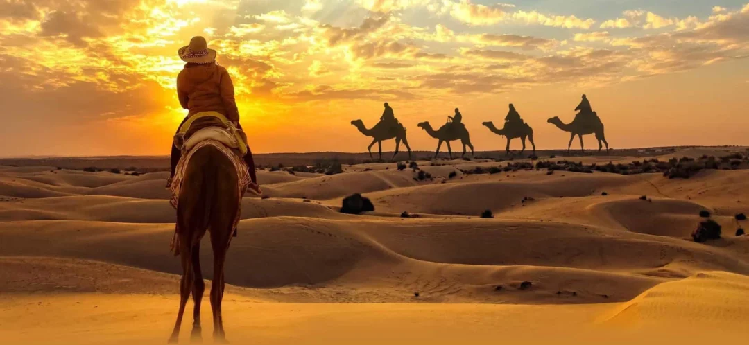 Tourist enjoying a camel ride Dubai experience across golden desert dunes at sunset