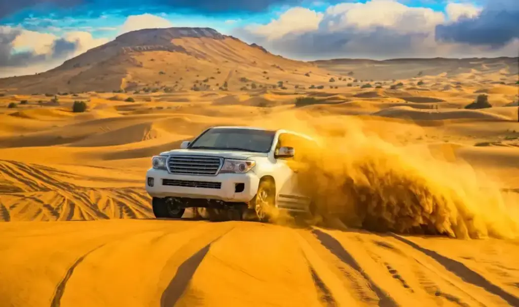 White Land Cruiser driving through sand dunes in the Sahara Desert near Dubai, creating a dramatic cloud of golden sand.