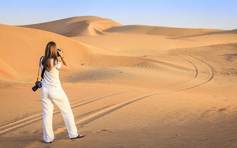 Tourist taking Desert Safari Dubai pictures during golden hour