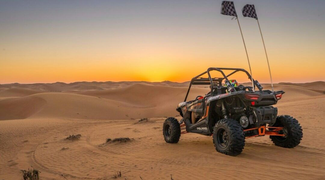 Dubai dune buggy tours with two-seater buggy driving over desert dunes at sunset