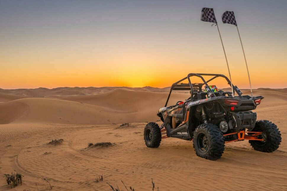 Dubai dune buggy tours with two-seater buggy driving over desert dunes at sunset