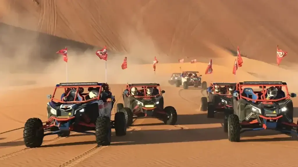 Dubai dune buggy tours with two-seater buggy riding over Dubai desert dunes at sunset
