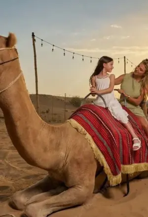 Tourist enjoying a sunset camel ride Dubai experience in the Arabian Desert