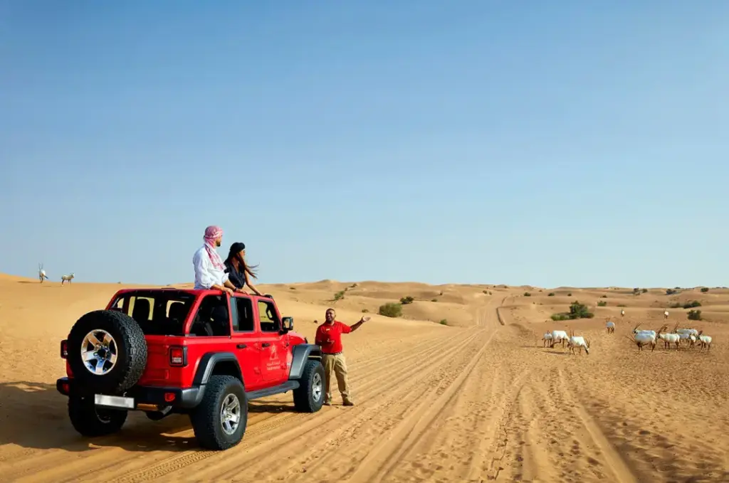 jeep safari Dubai 4x4 on red dunes at sunset with riders