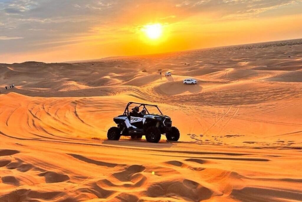 Dubai dune buggy tours with two-seater buggy riding over Dubai desert dunes at sunset