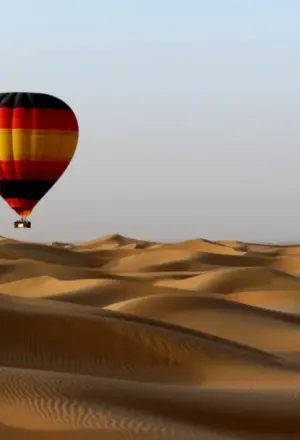 Dubai Desert Safari 4×4 on red dunes at sunset with lantern-lit camp