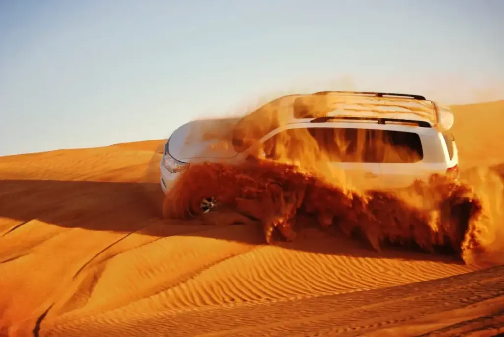 4x4 Dune Bashing Adventure – Desert Safari Abu Dhabi › Forever Tourism LLC A 4x4 SUV performing thrilling dune bashing over the red sands during a Desert Safari Abu Dhabi.
