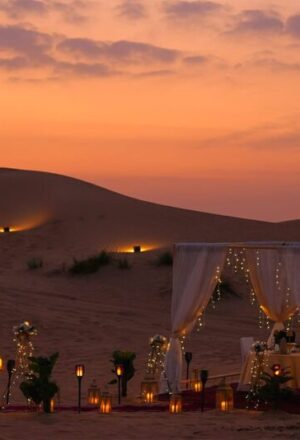 › Forever Tourism LLC private dinner Dubai desert setup with candles on red dunes at sunset
