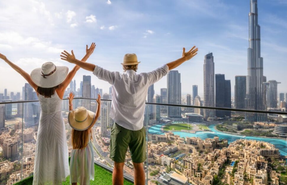happy family on a package tour holiday with luggage and city and desert in background