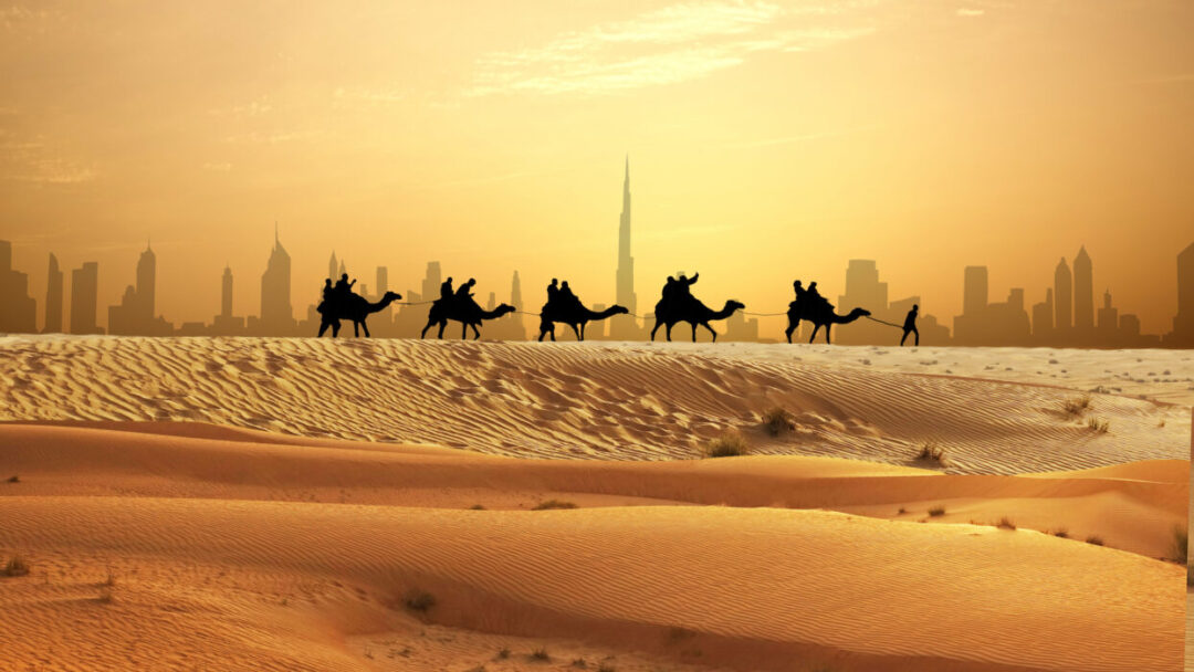 Camel caravan crossing golden dunes with Dubai skyline during a desert Dubai experience