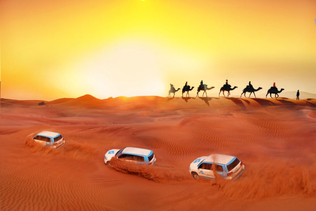 VIP desert safari with BBQ dinner featuring dune bashing vehicles and camel caravan at sunset in Dubai desert.