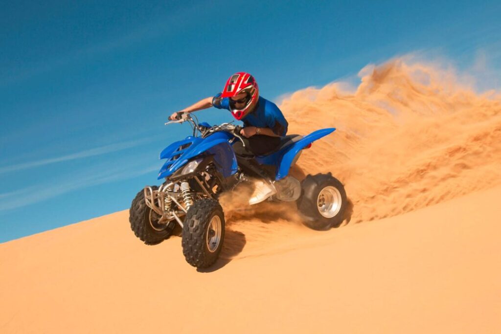 ATV desert safari Dubai rider driving quad bike on red dunes
