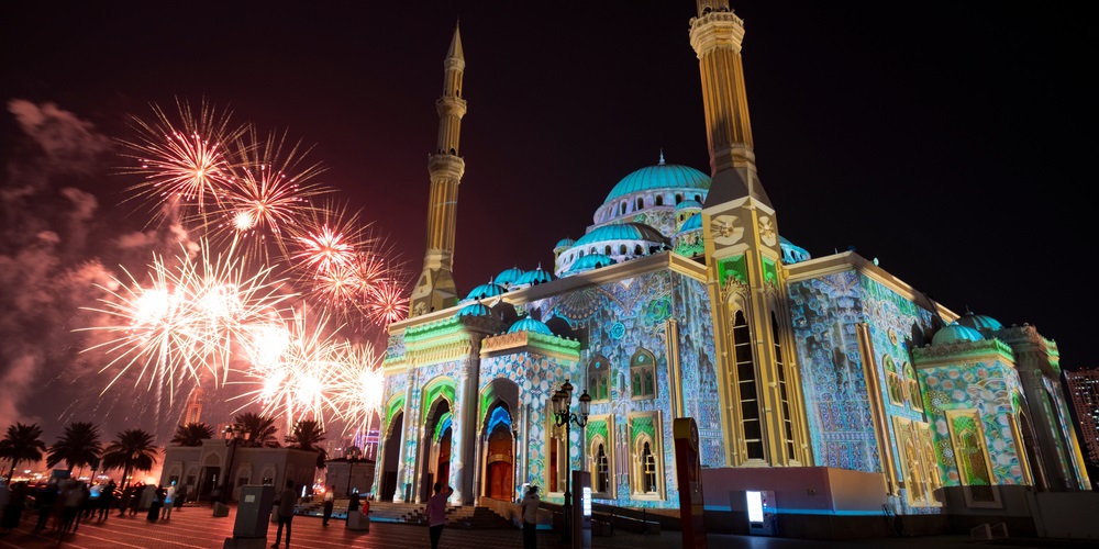Fireworks in Sharjah lighting up the night sky near a grand mosque, showcasing a vibrant cultural celebration and festive atmosphere.