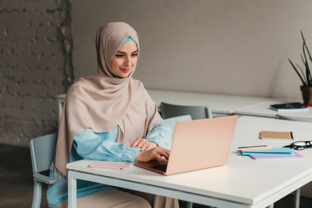 Muslim woman working on laptop in office during Ramadan reflecting Ramadan working hours UAE adjustments