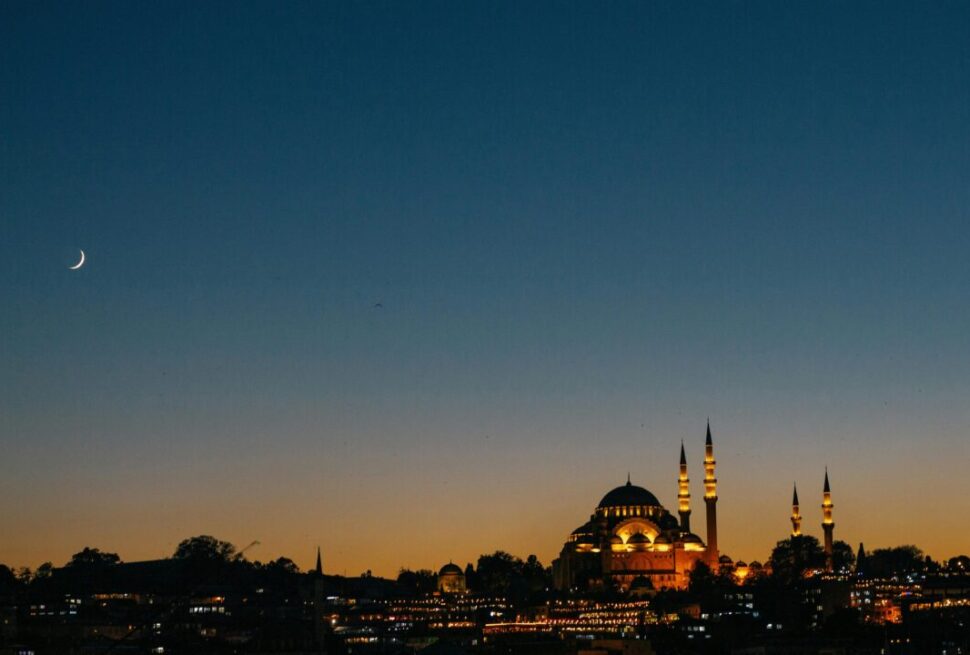 Illuminated mosque skyline at sunset with crescent moon – one of the beautiful countries to visit this Ramadan