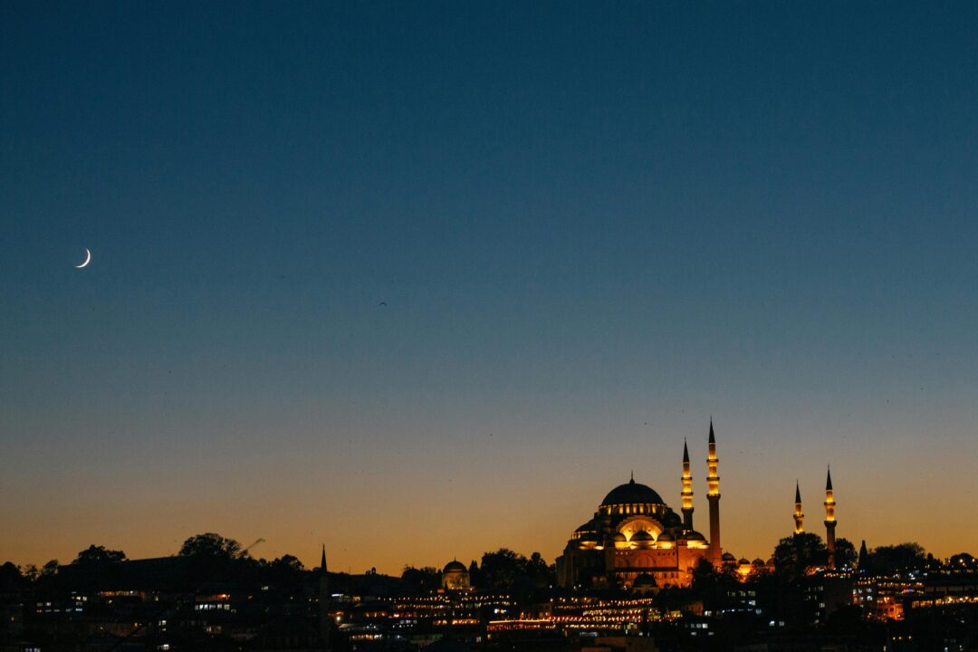 Illuminated mosque skyline at sunset with crescent moon – one of the beautiful countries to visit this Ramadan