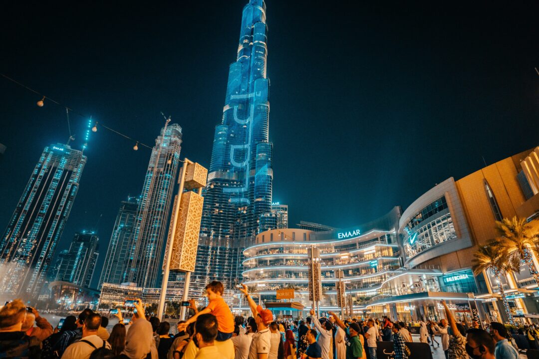 Dubai in Ramadan at night with crowds gathered near Burj Khalifa and Dubai Mall, illuminated skyline and festive atmosphere.