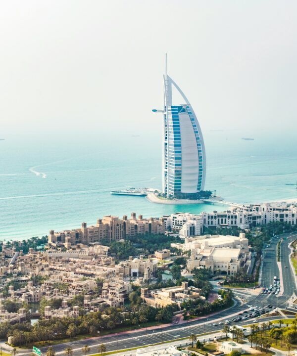 Aerial view of Dubai coast with the sail-shaped Burj Al Arab hotel on the water and surrounding buildings.