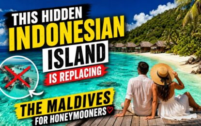 This Hidden Indonesian Island Is Replacing the Maldives for Honeymooners › Forever Tourism LLC YouTube thumbnail showing a couple in white on a wooden deck overlooking turquoise lagoon and overwater bungalows; bold yellow and white text claims Indonesian island replacing the Maldives for honeymooners.