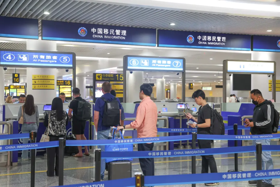 Airport immigration counters for China Immigration with travelers lining up and staff at booths in a large terminal area.