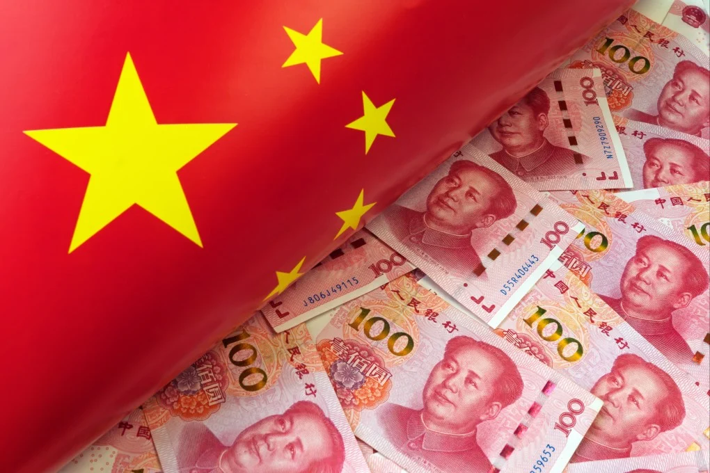 Flag of China draped over a pile of 100 yuan banknotes, featuring Xi Jinping portraits, signaling economic themes.