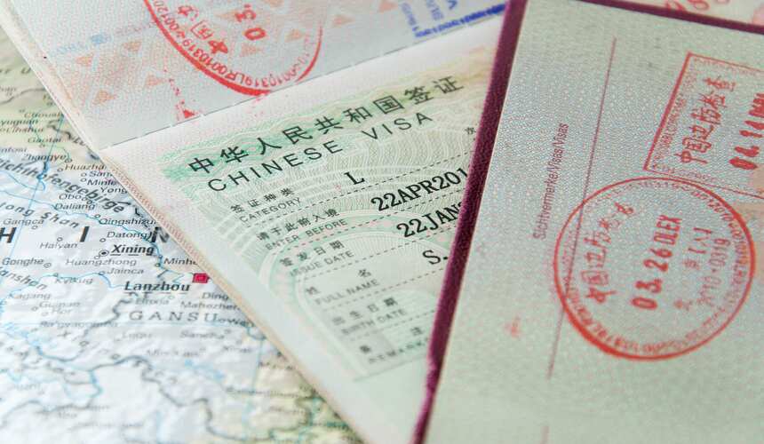 Close-up of a Chinese visa page and passport on a map, with red stamps and official text visible.