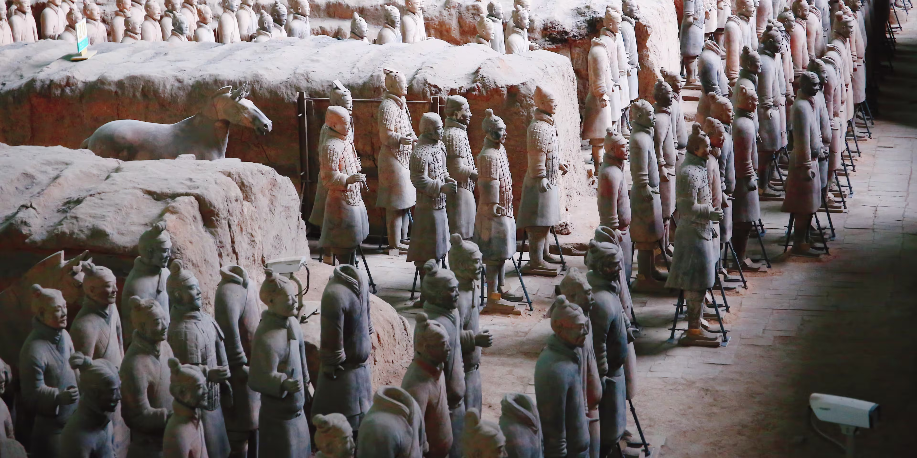 Rows of life-sized Terracotta Army statues standing in pits, part of China's ancient mausoleum exhibit.