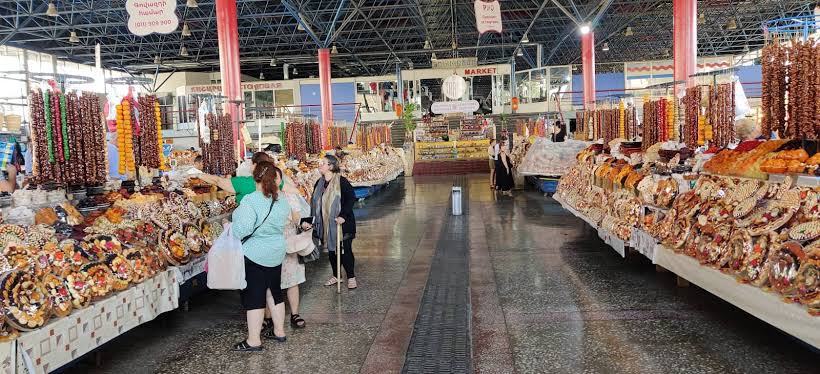 Indoor market with colorful garlands and sweets on both sides, shoppers browsing the stalls.