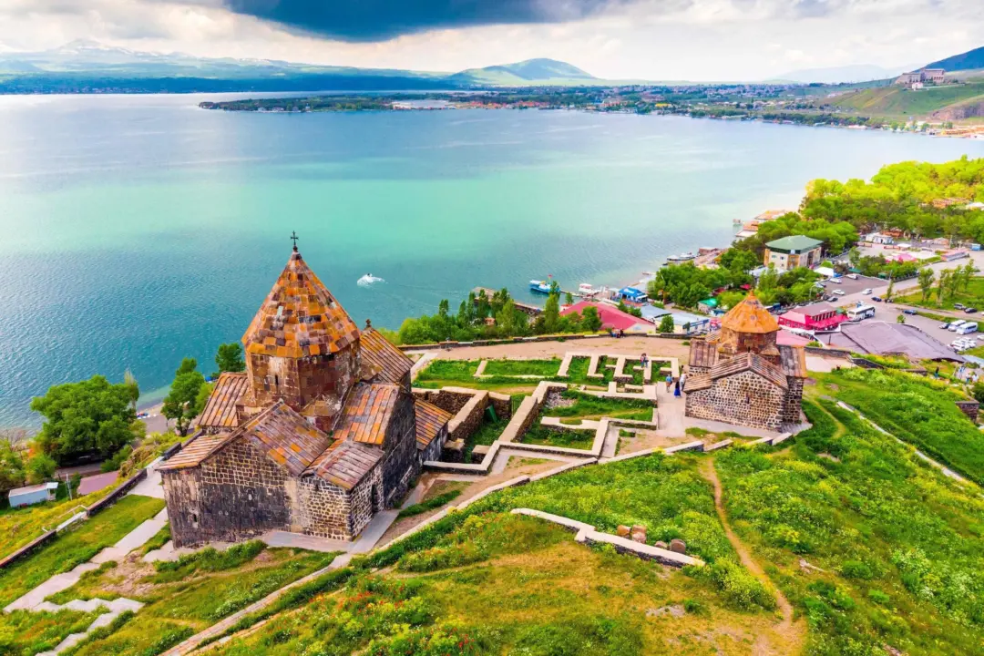 A historic stone church and fortress on a hill overlooking a turquoise lake.